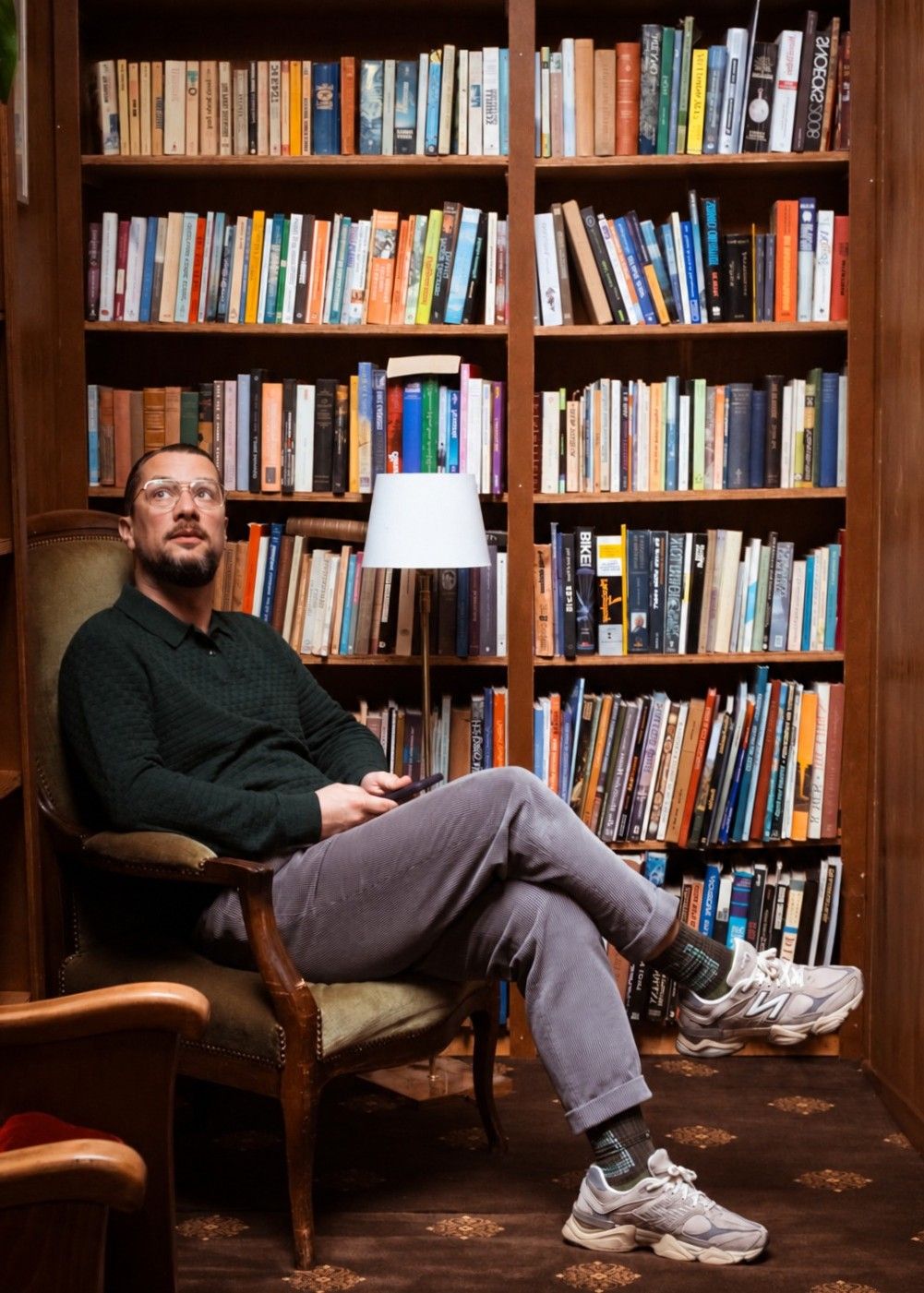 Paul Baptista in a leather armchair in front of a wall of books.